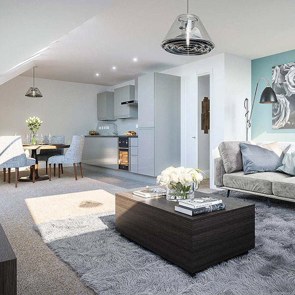 Open-plan living at The Coach House under a vaulted white ceiling with roof lights: a pale grey kitchen, a dining set beyond, a dark oak coffee table on a deep grey rug and a grey sofa.